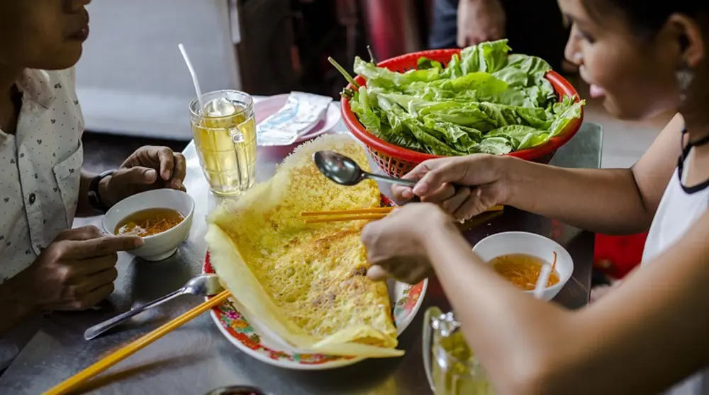 Cutting Vietnamese pancake (Banh Xeo) using spoons and chopsticks