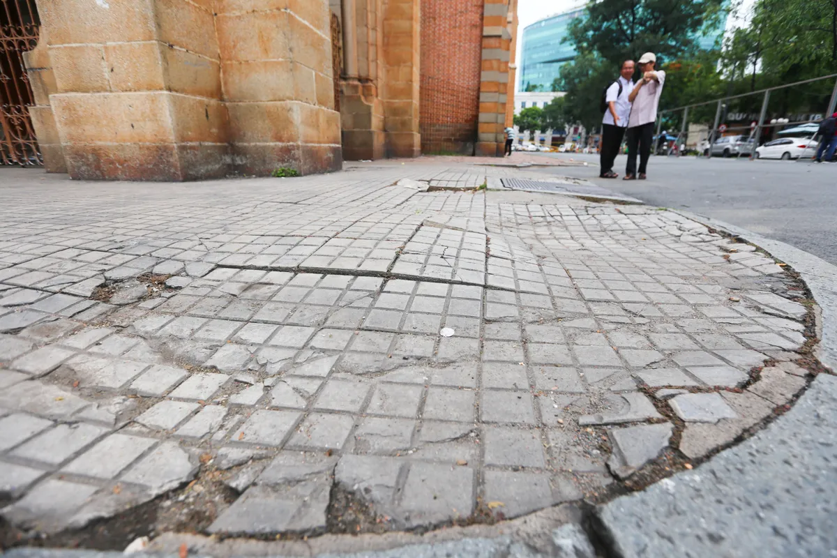 The surrounding sidewalk area and the layer of bound stone are peeling off, and the stone is broken, creating protrusions