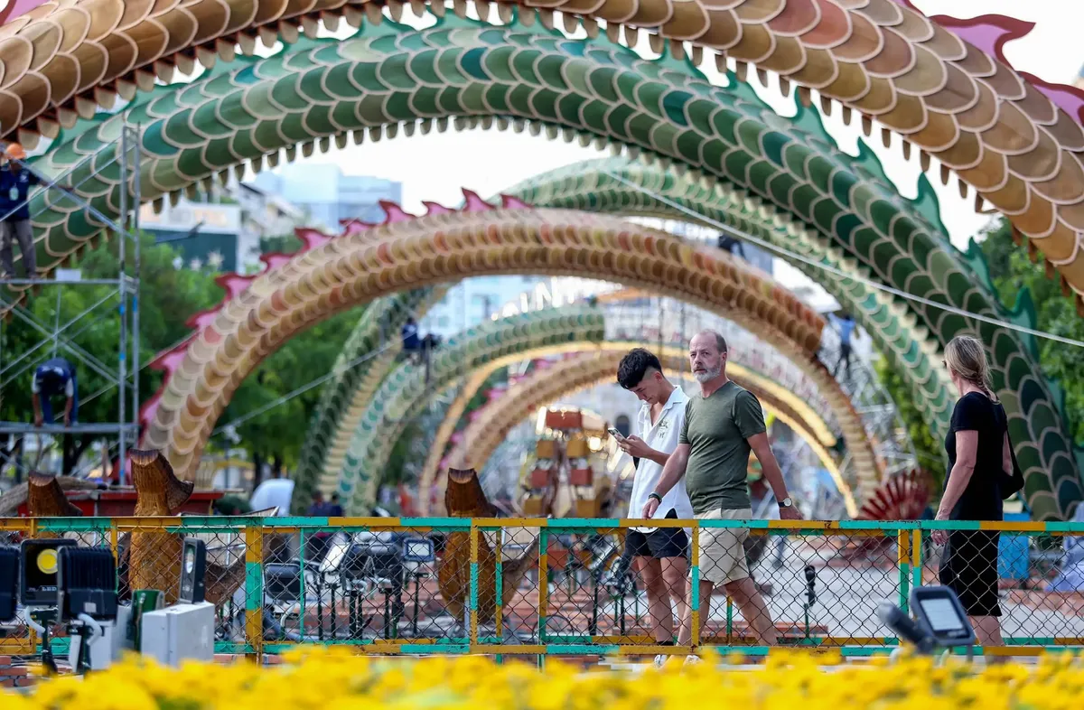 Tourist walking by the dragon figure on Nguyen Hue Flower Street