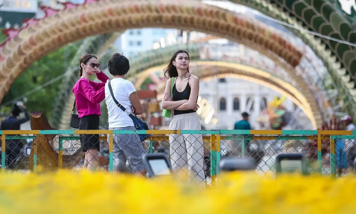 Tourists walking by the dragon figure on Nguyen Hue Flower Street