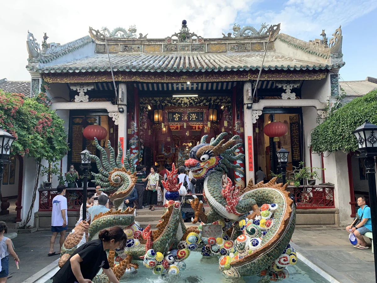 A colorful dragon sculpture stands before the ornate Cantonese Assembly Hall in Hoi An.