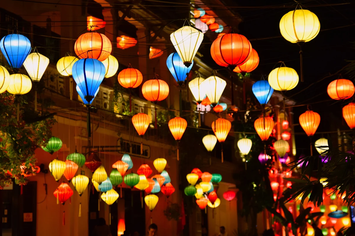 Colorful silk lanterns glow above a street in Hoi An at night.