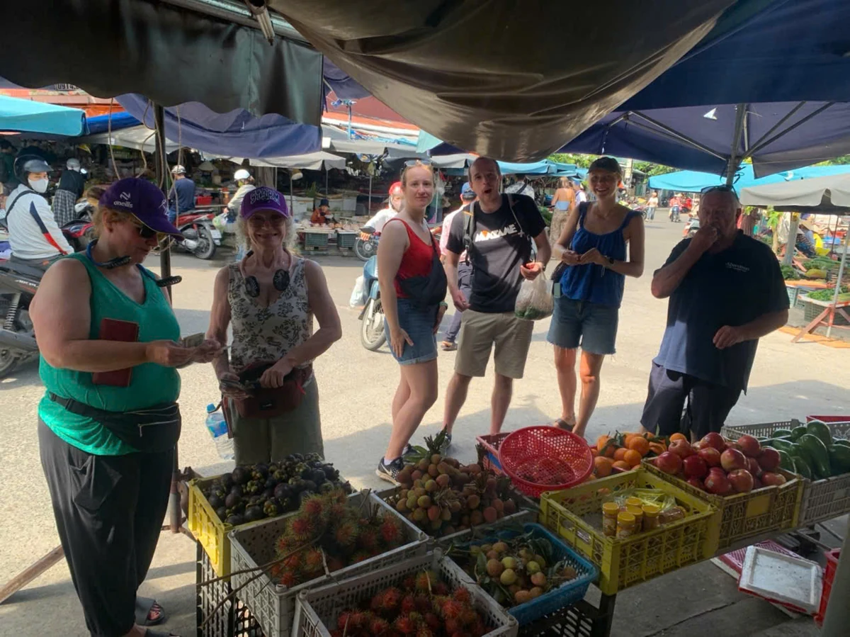 Visitors gathered at a fresh-produce stall during a cooking-class market visit.
