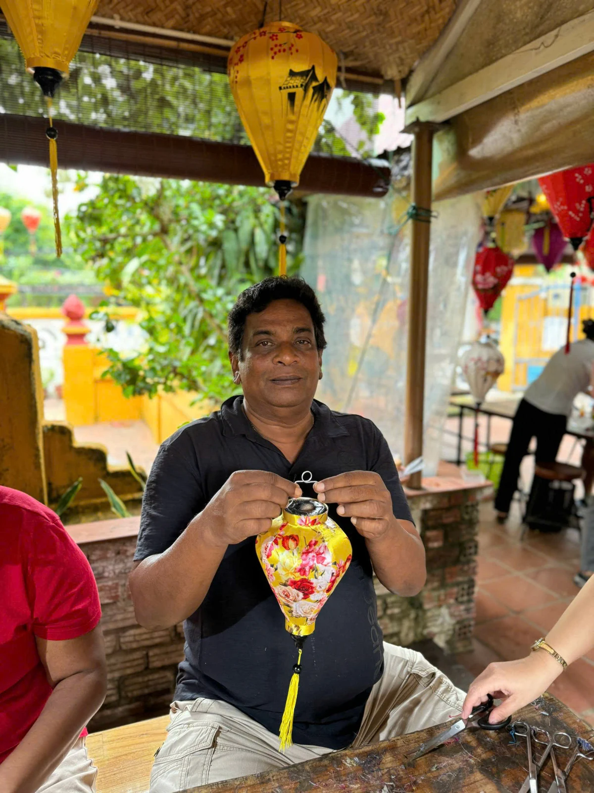 A participant holding a completed yellow floral lantern during a lantern-making workshop.