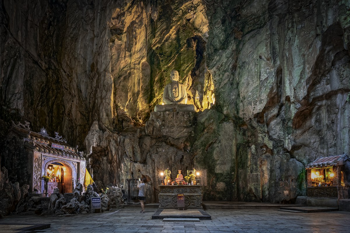 Buddha statue and illuminated shrines inside Huyen Khong Cave in the Marble Mountains, Da Nang.