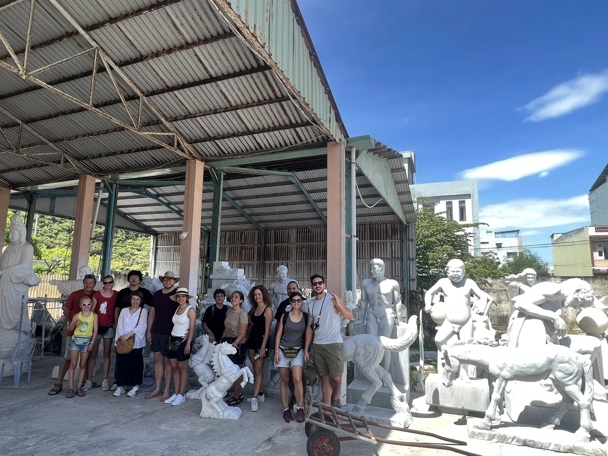 Visitors standing among large carved stone figures in a sculpture showroom.