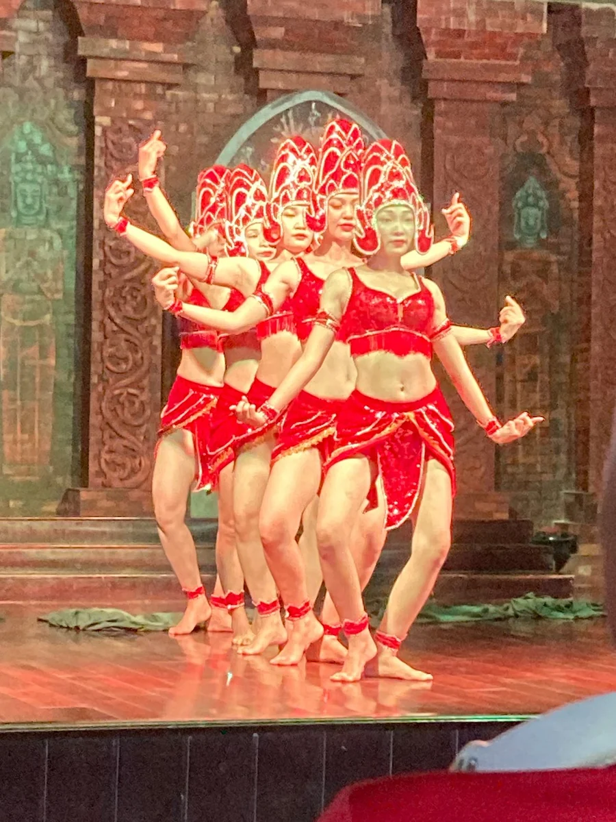 Dancers in red costumes and ornate headdresses performing on a stage at My Son Sanctuary.