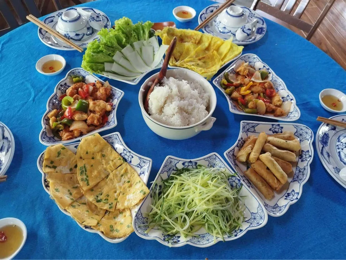 Rice, vegetables and shared dishes laid out on a table in the supplier's My Son tour meal photo.
