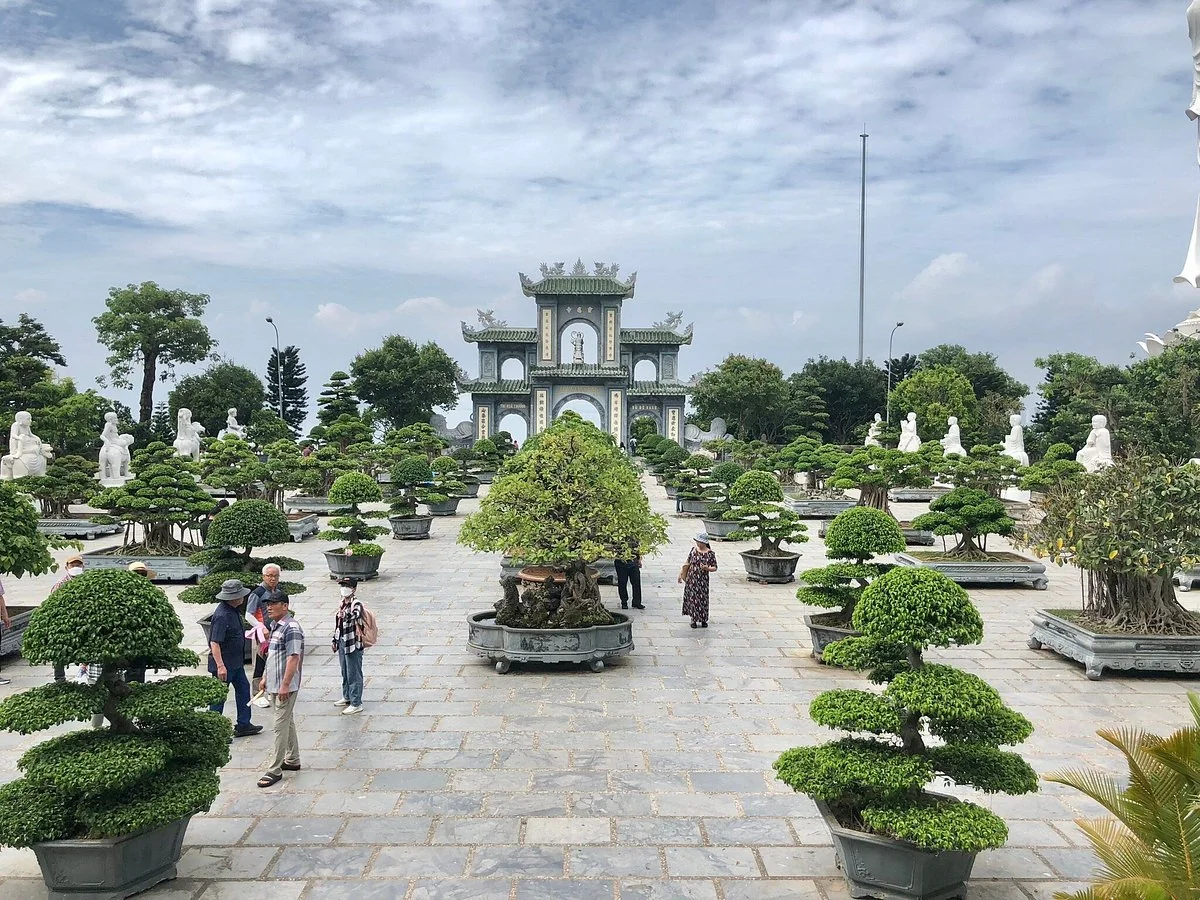Bonsai trees and stone statues lining the courtyard towards the gate of Linh Ung Pagoda on Son Tra Peninsula.